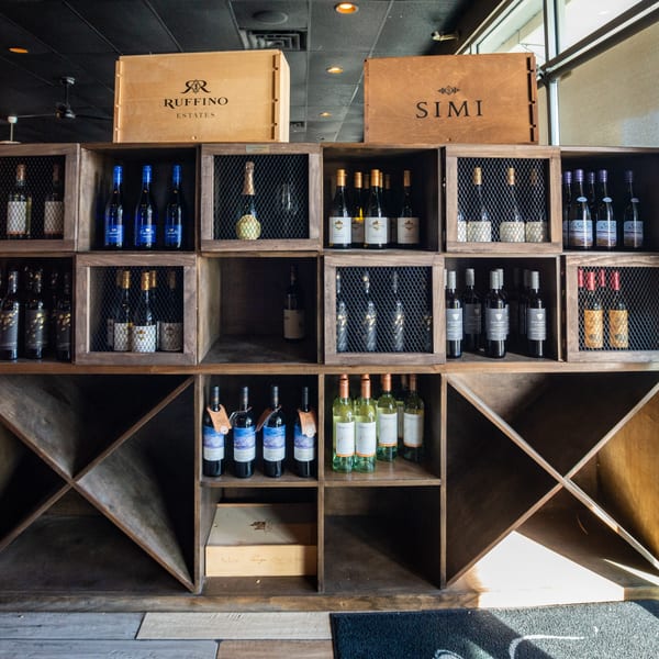 A wooden wine rack filled with various bottles of wine, including Ruffino Estates and Simi brands.